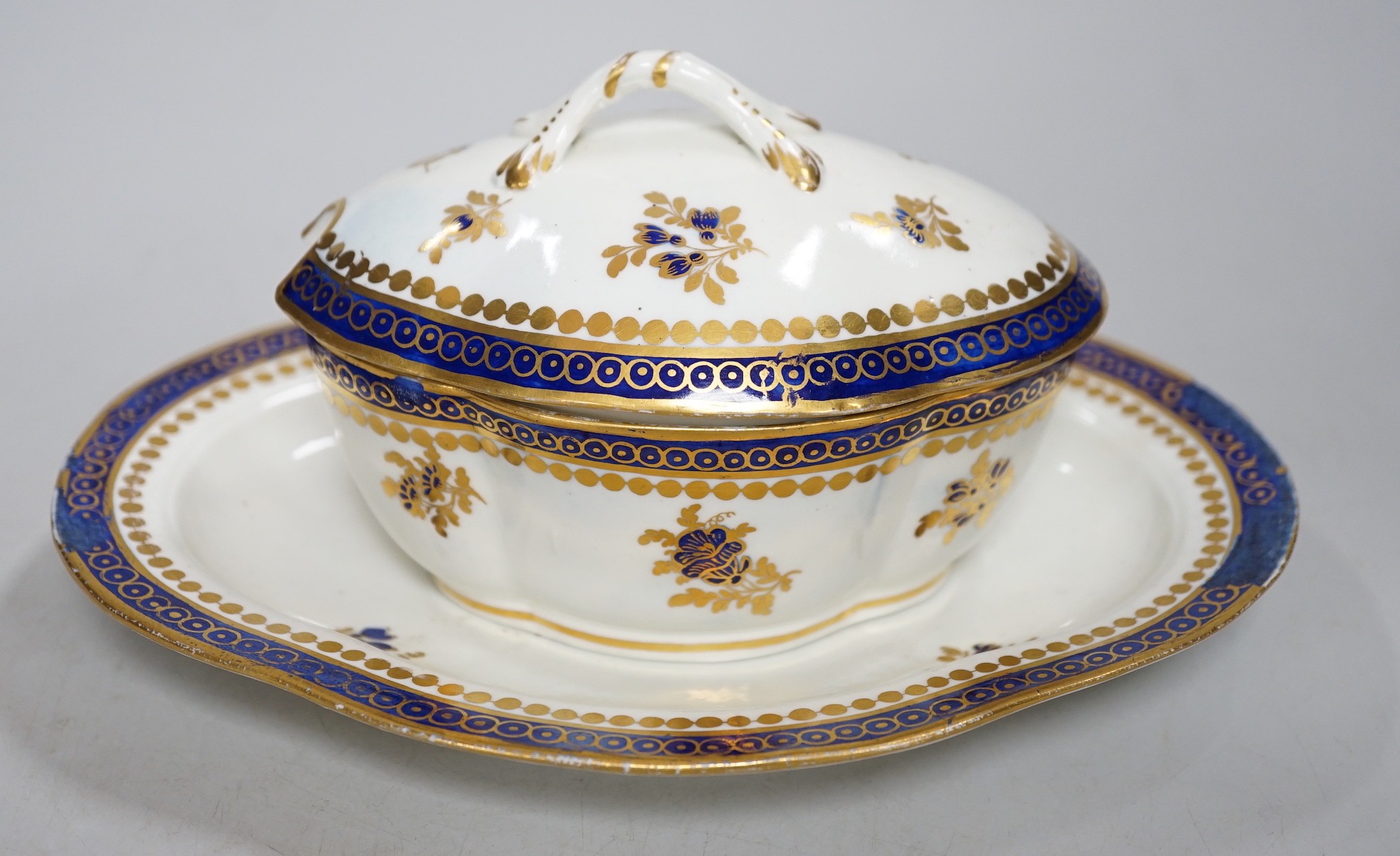An 18th century Caughley tureen cover and stand with blue and gilt decoration, stand mis-fired to border, S mark to stand and base. 15cm wide